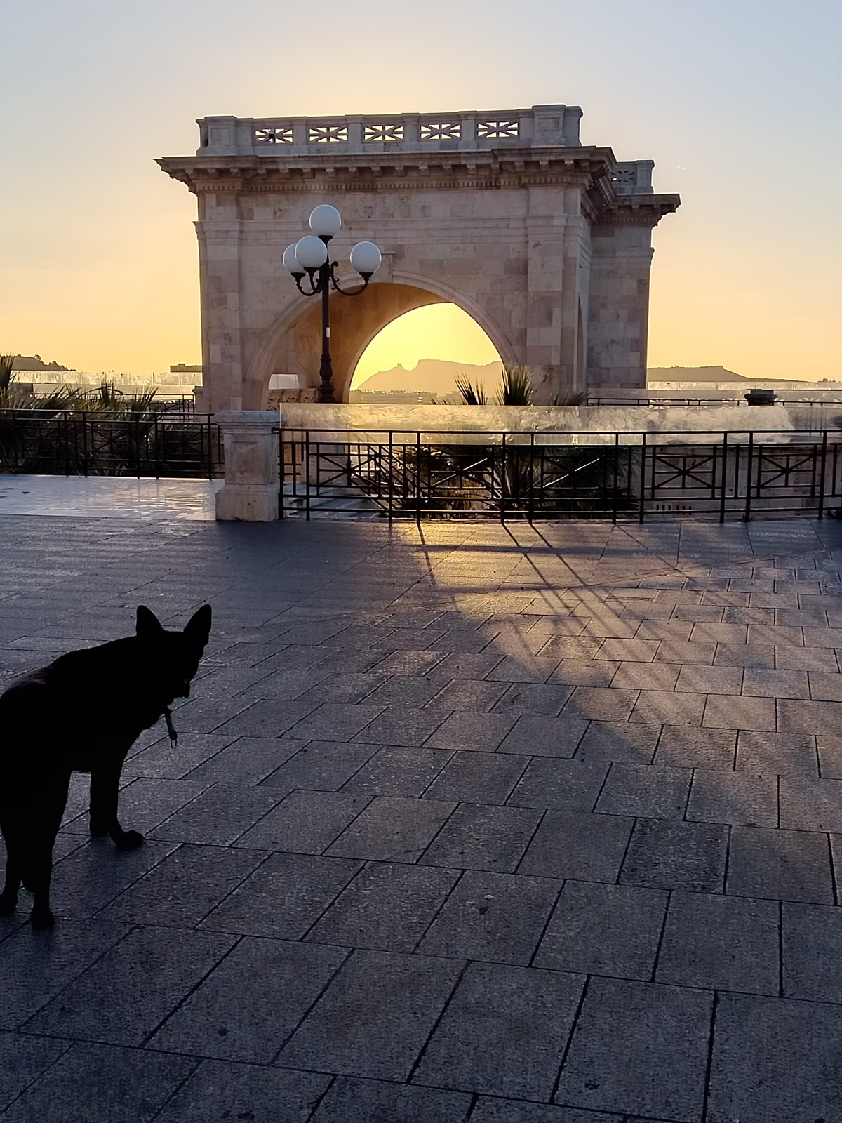 Mia silhouetted at sunset beside a stone arch in Sardinia